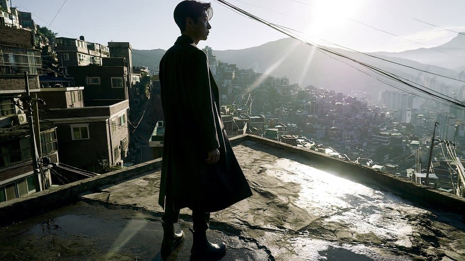 강한 햇빛이 드는 옥상에 선 코트 차림의 남자
